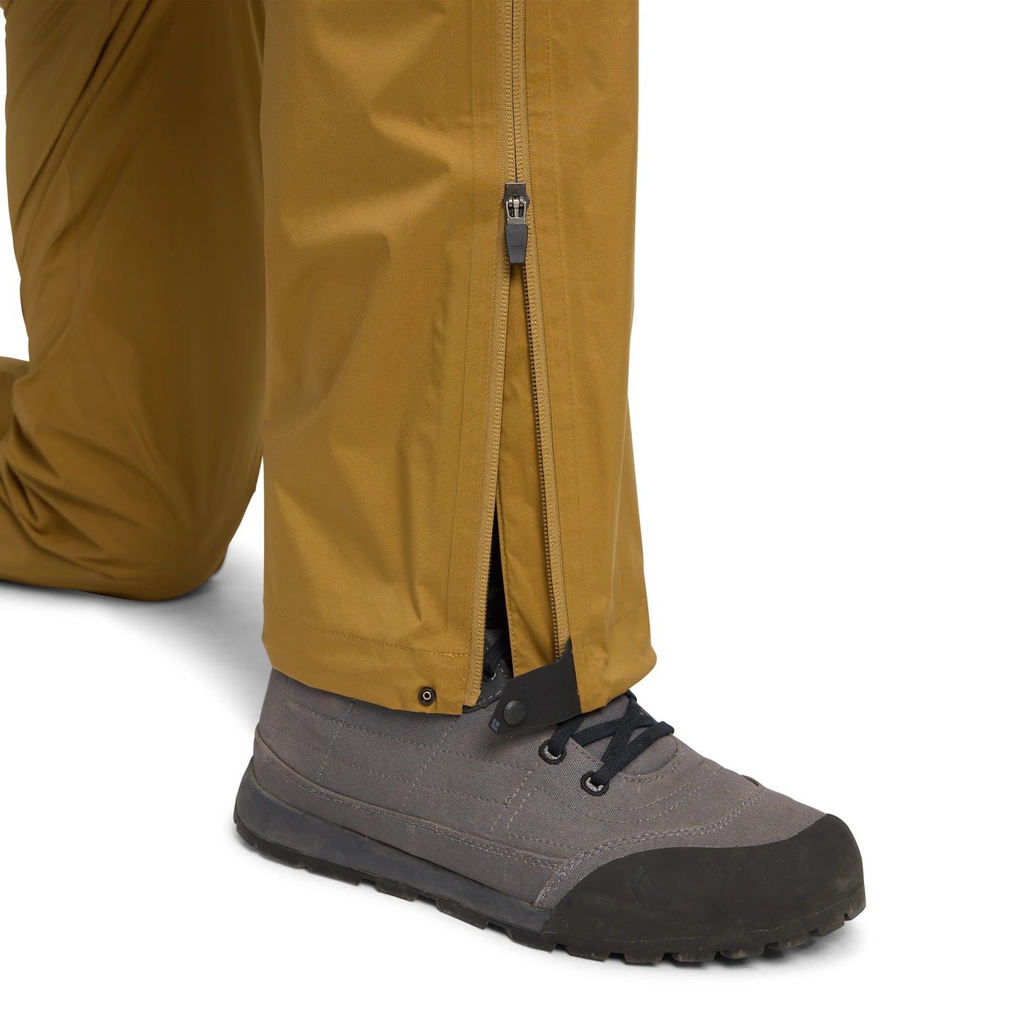 Close-up of brown pants with a zipper and gray hiking boots on a white background