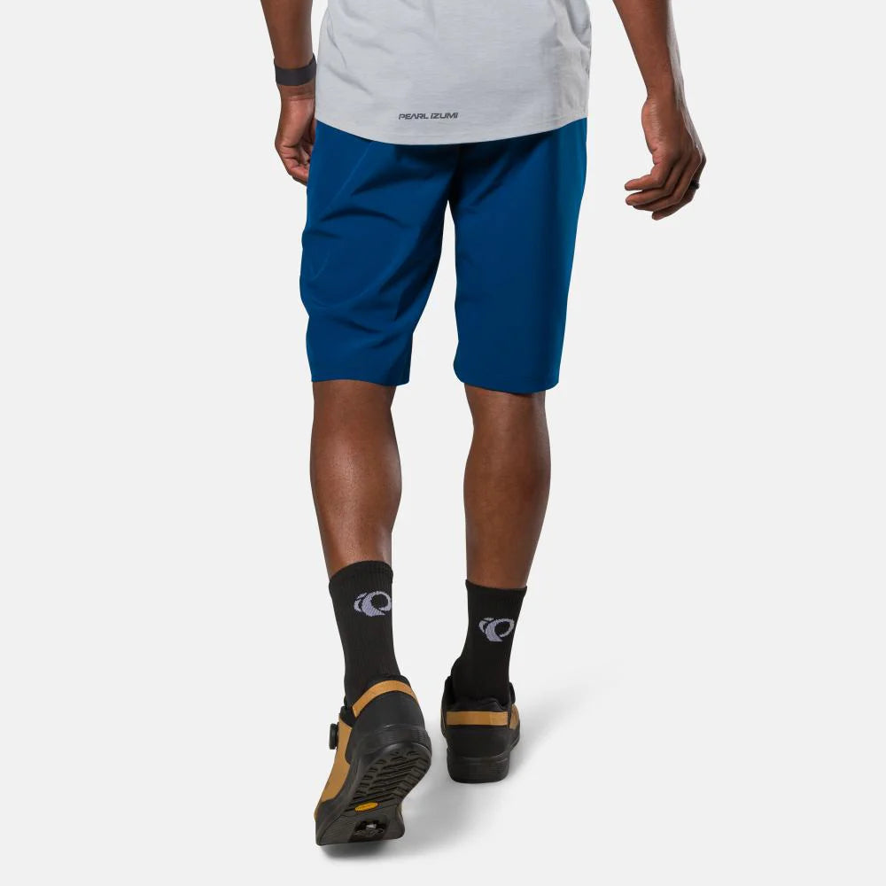 Person wearing blue shorts, black socks, and hiking shoes on a white background