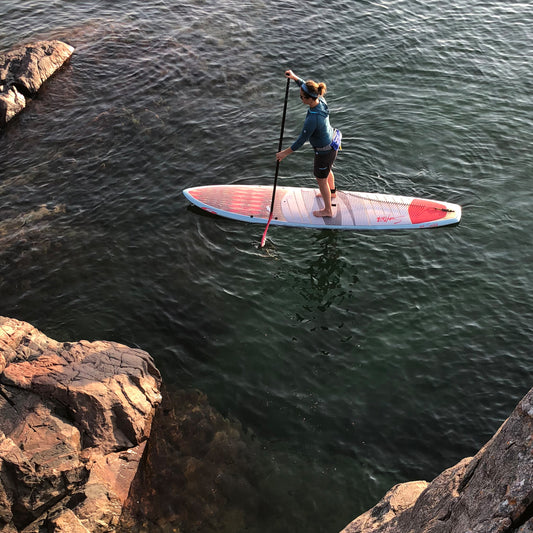 Young woman Stand Up Paddling on the blue waters of Lake Superior near Marquette Michigan