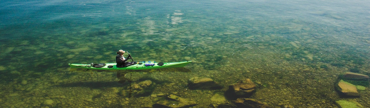 Woman paddling a kayak on crystal clear water