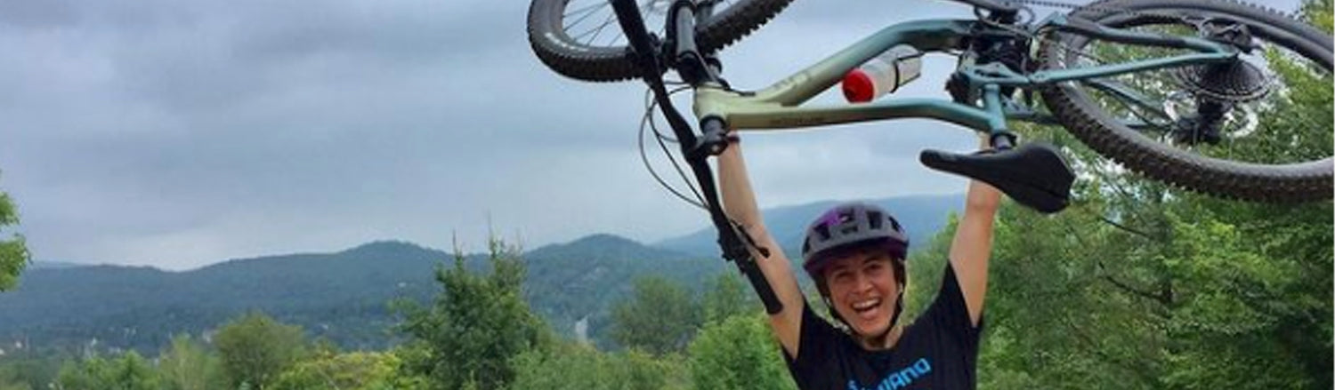 Liv women's mountain bike held over a riders head in excitement over the great trails in the Upper Peninsula