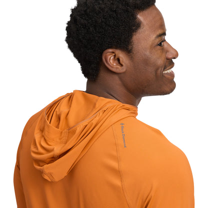 Man wearing an orange hoodie with a visible brand logo on a white background