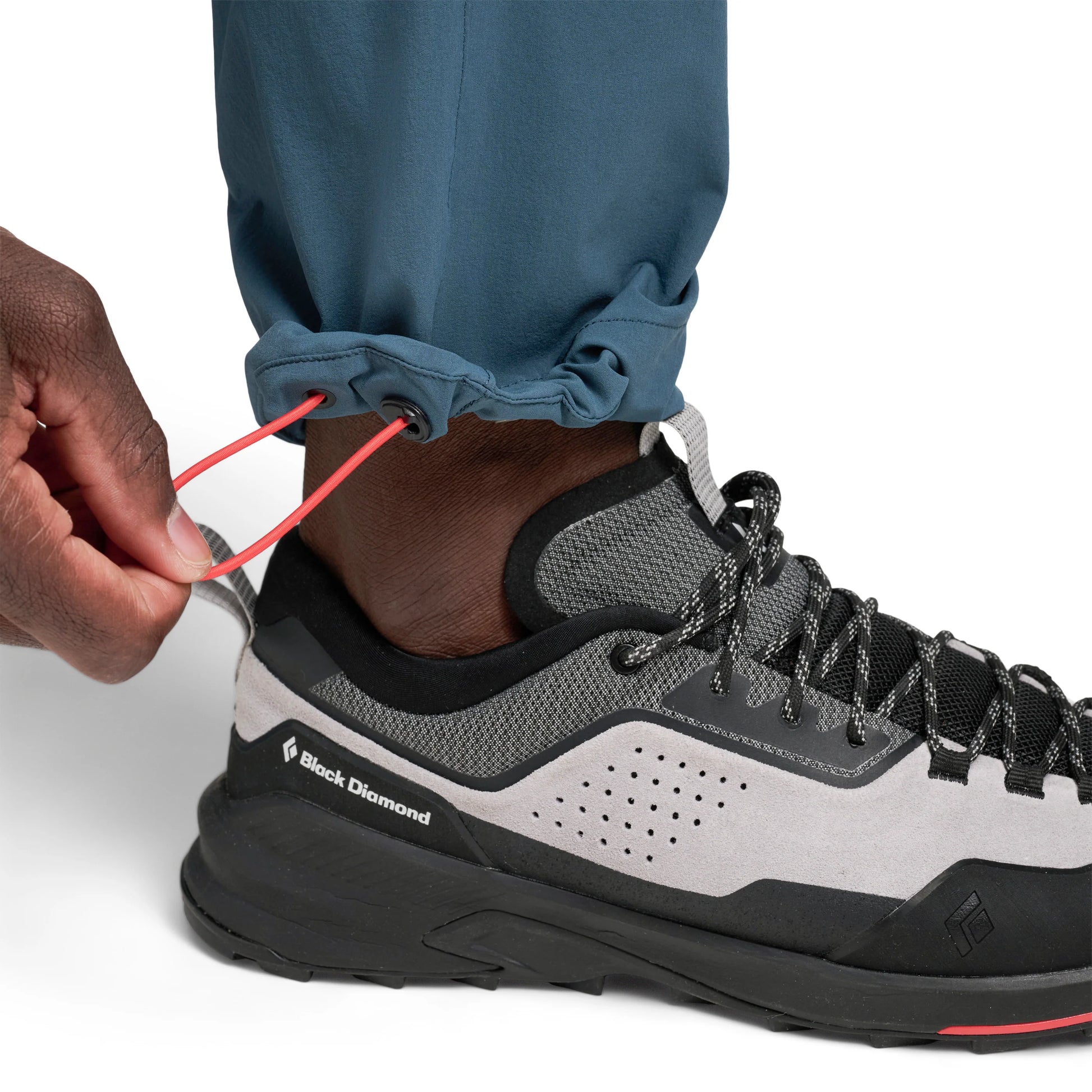 Person tying a shoelace on a Black Diamond hiking shoe with a white background
