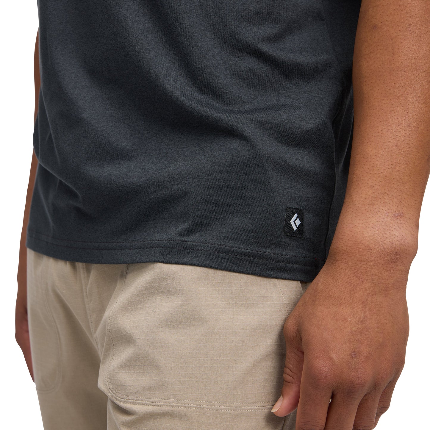 Person wearing a dark gray t-shirt with a small logo on a white background