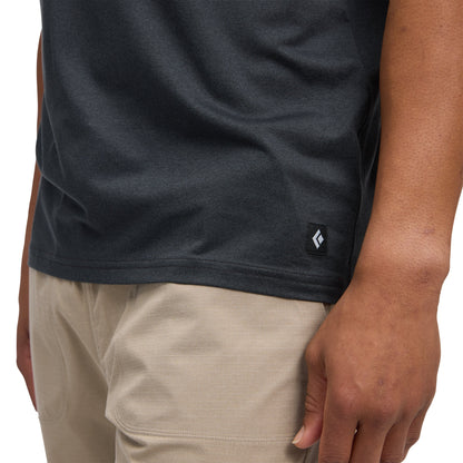 Person wearing a dark gray t-shirt with a small logo on a white background