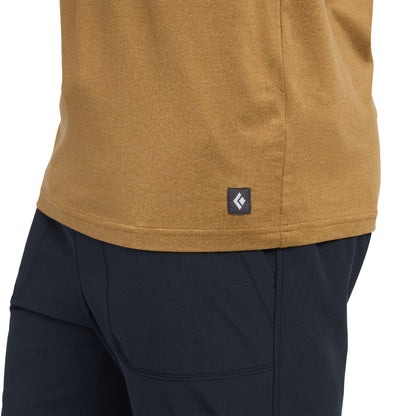 Close-up of a mustard yellow shirt with a Black Diamond logo and black pants on a white background