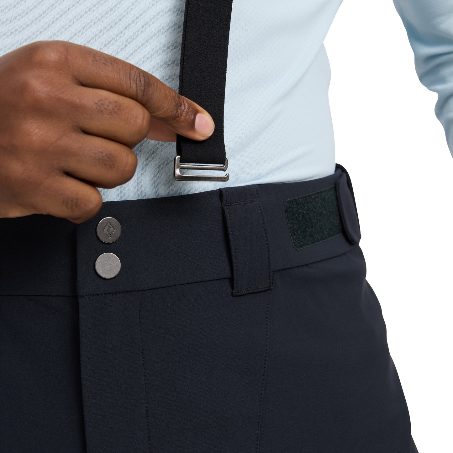 Person wearing navy pants with suspenders and a light blue shirt, focusing on the pants and suspenders.