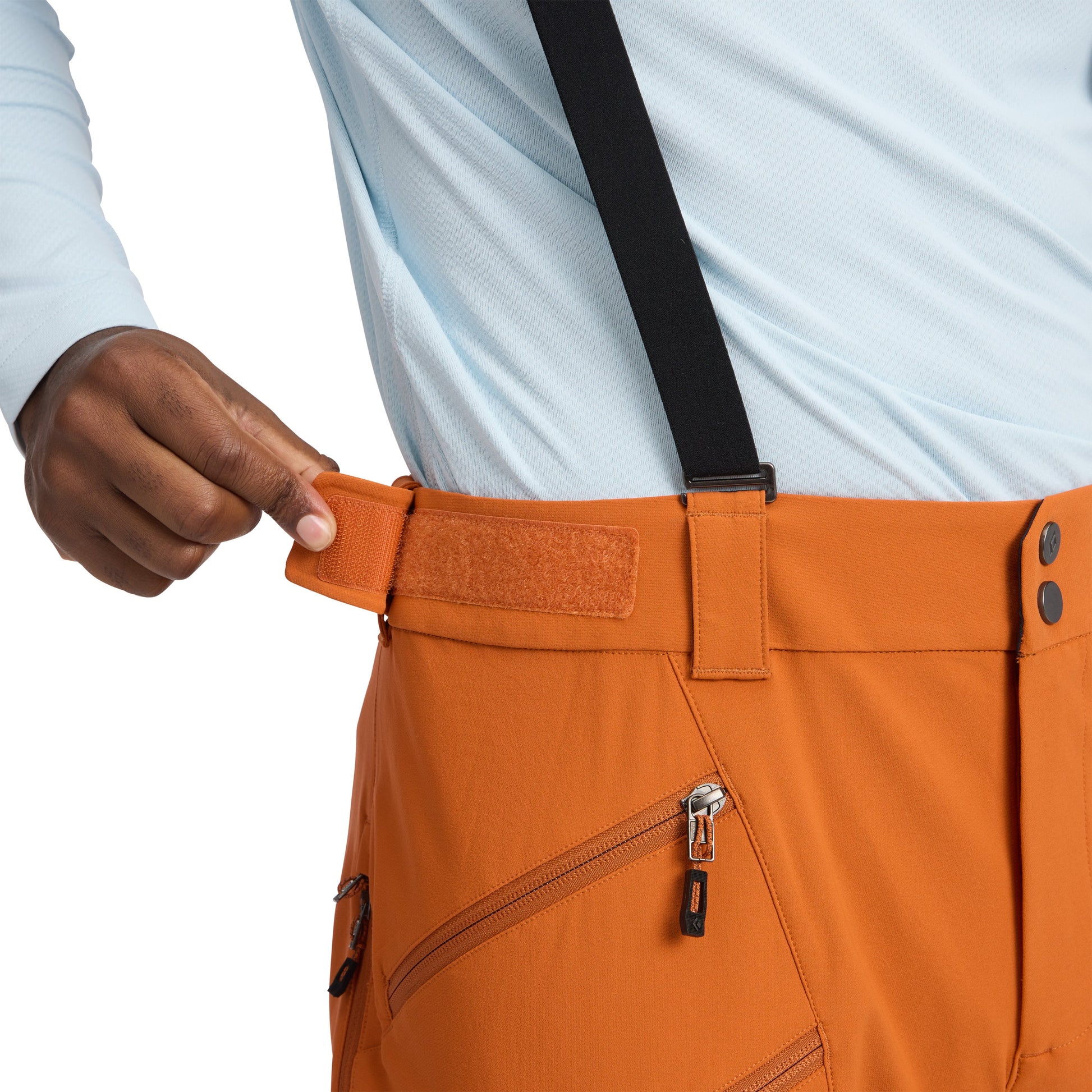 Person wearing orange pants with a focus on the waistband and zipper.