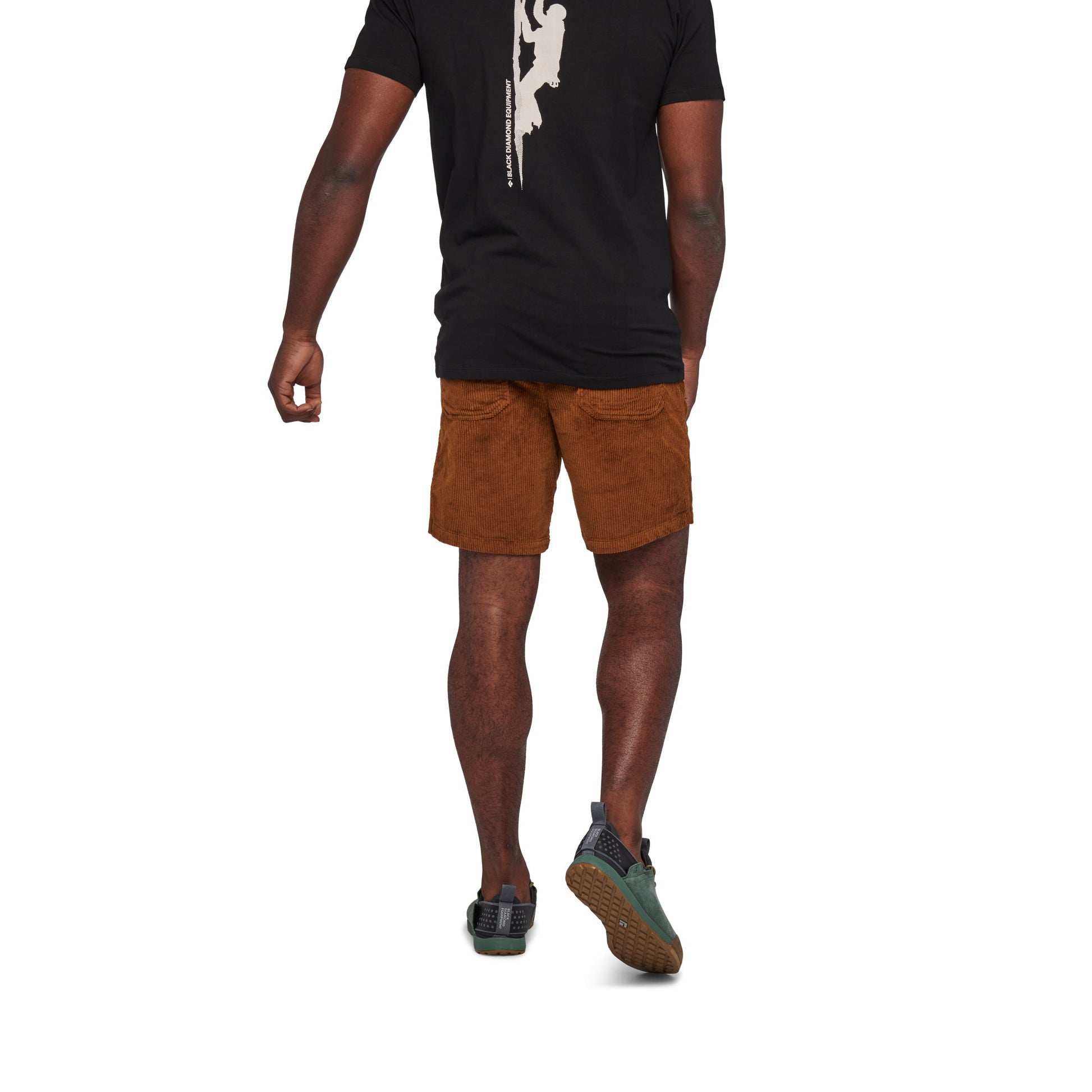 Person wearing a black t-shirt with a white graphic and brown shorts on a white background