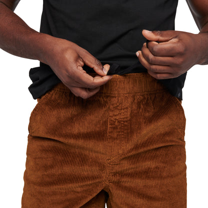 Person wearing brown corduroy pants and a black shirt on a white background