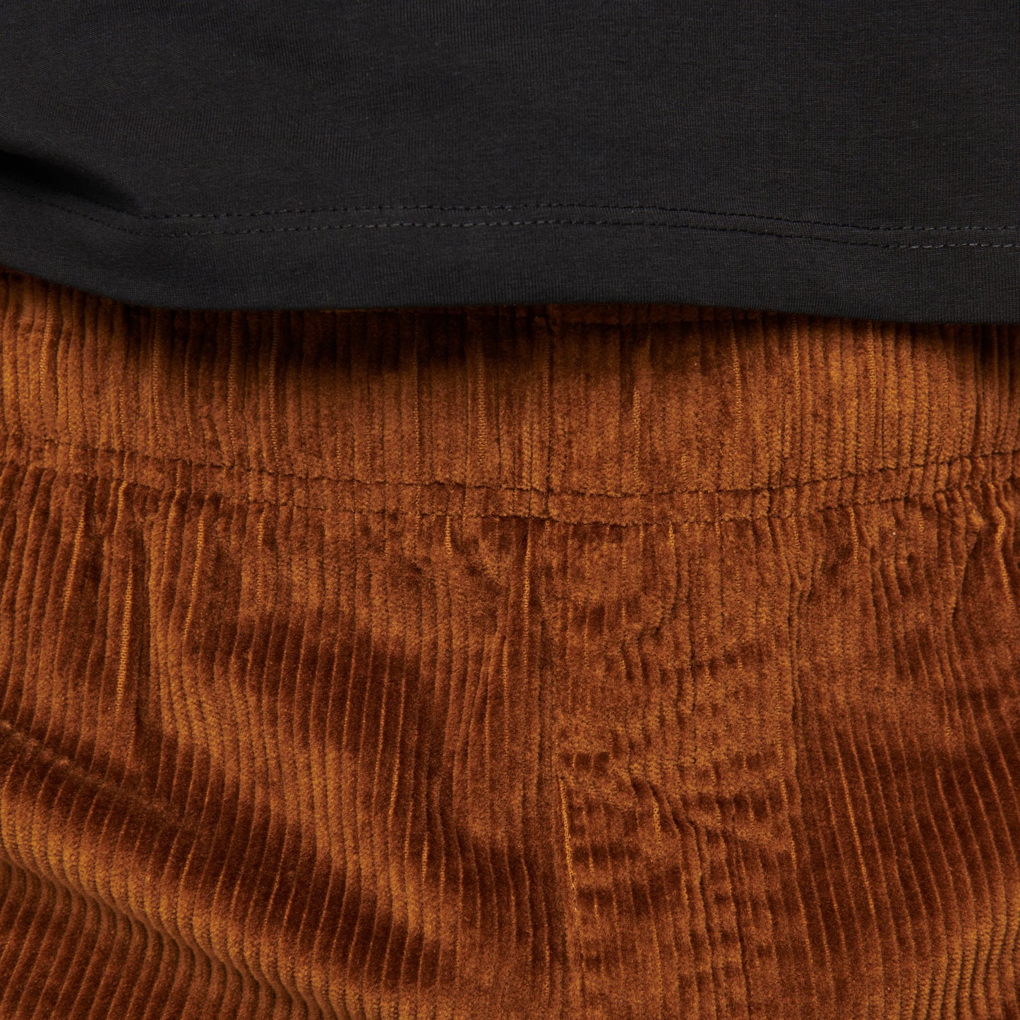 Close-up of brown corduroy pants with a black shirt underneath.