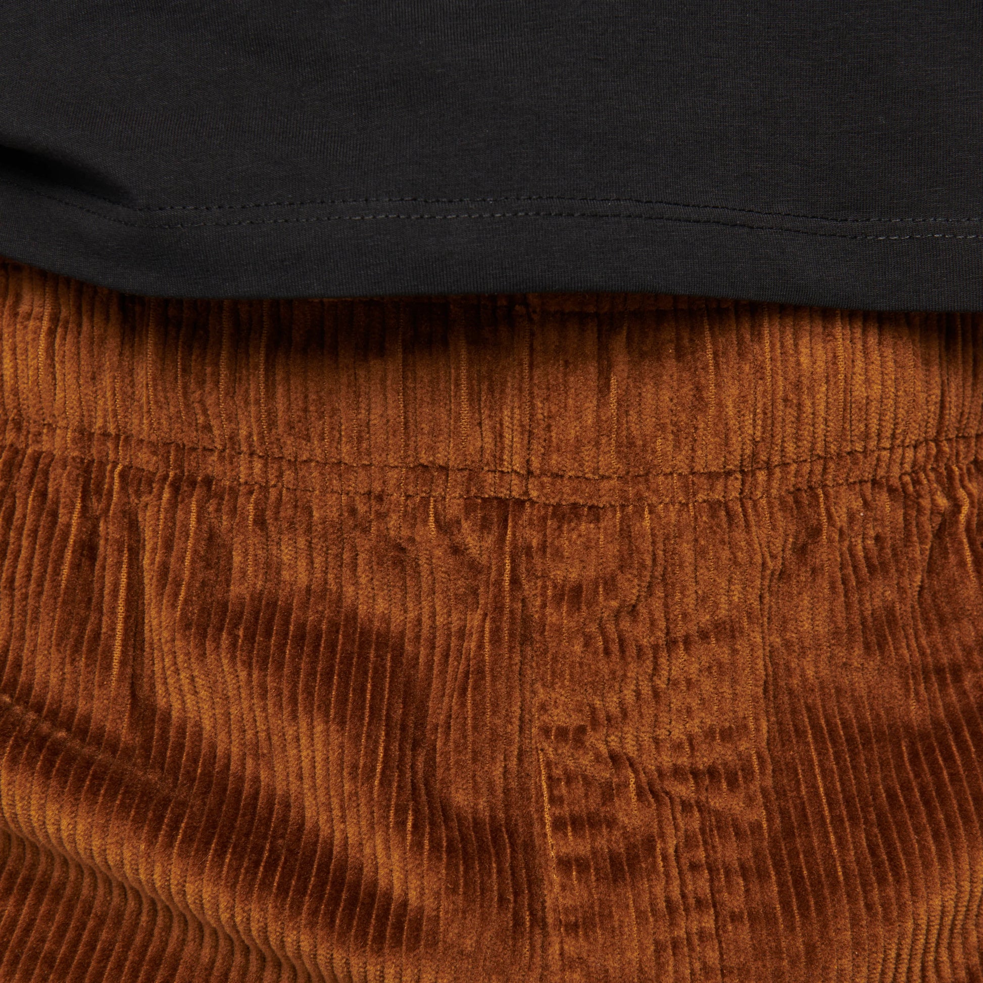Close-up of brown corduroy pants with a black shirt underneath.