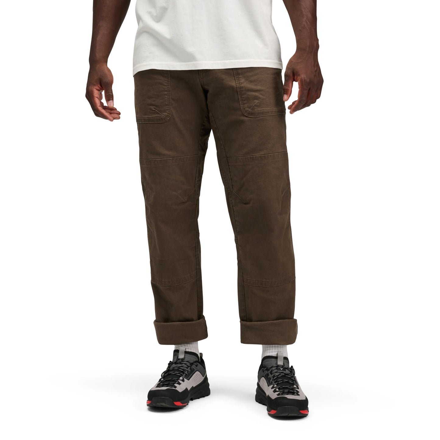 Person wearing brown pants and black hiking shoes on a white background