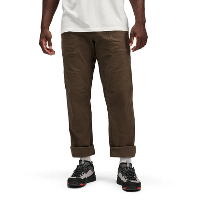 Person wearing brown pants and black hiking shoes on a white background