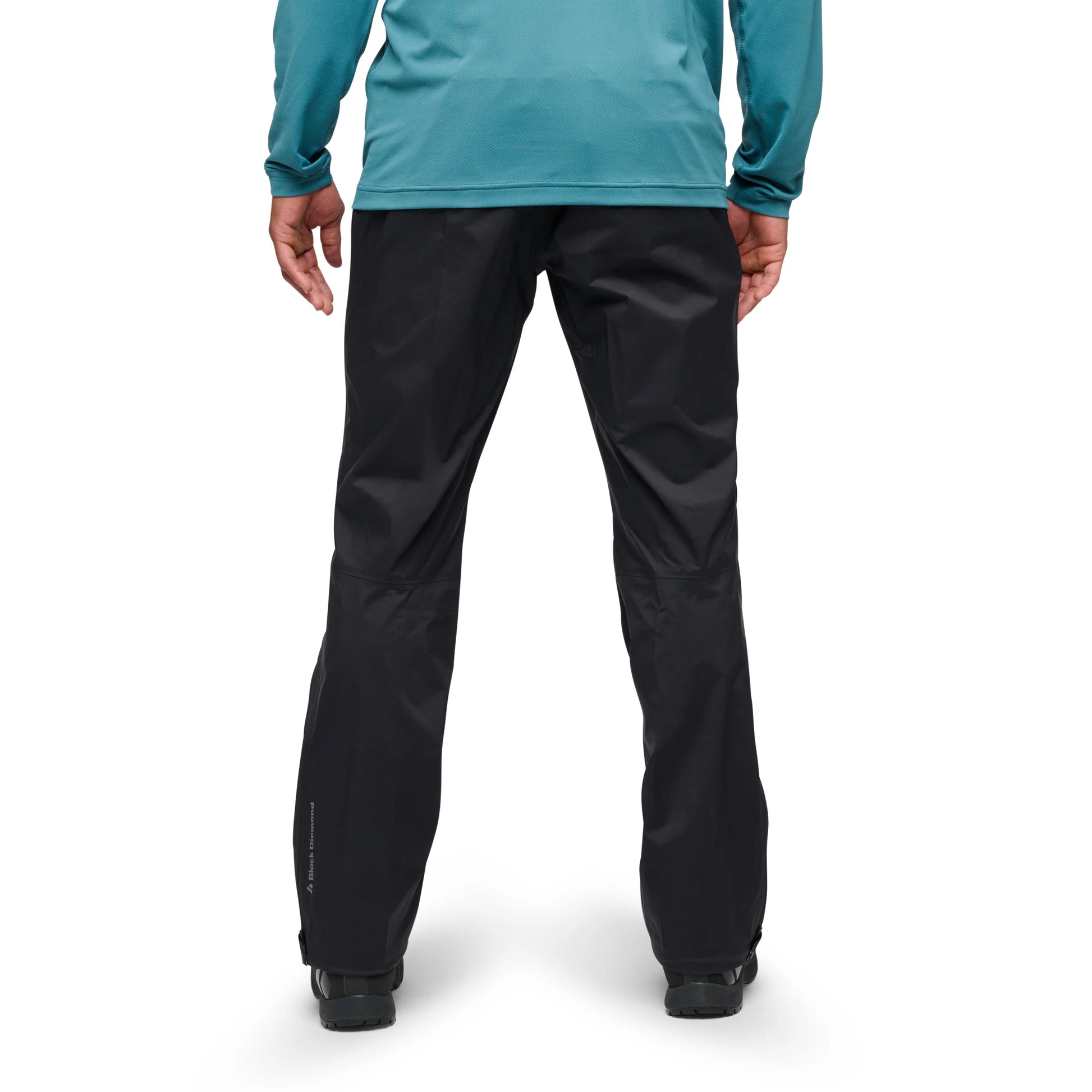 Person wearing black pants and a teal long-sleeve shirt on a white background