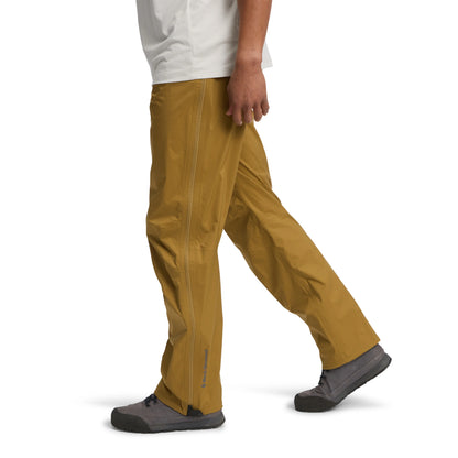 Person wearing mustard yellow pants and dark shoes on a white background
