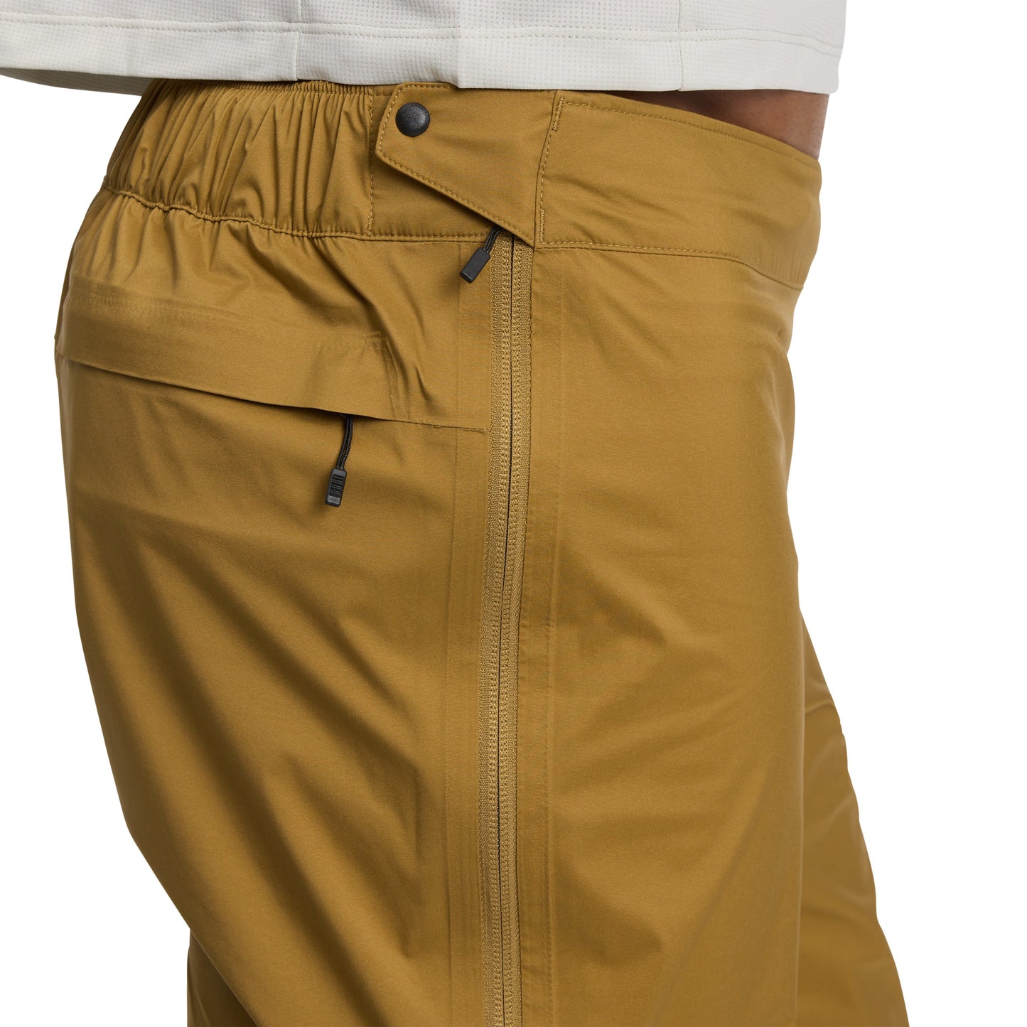 Close-up of mustard yellow pants with a white shirt underneath on a white background