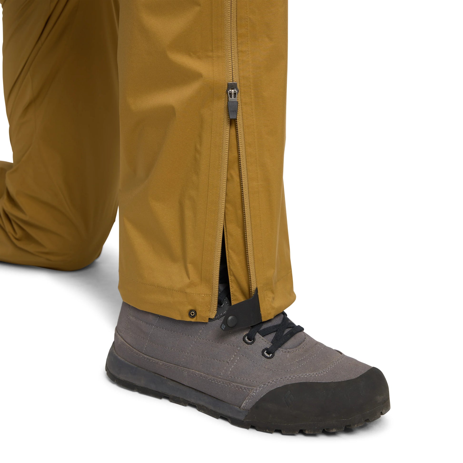 Close-up of brown pants with a zipper and gray hiking boots on a white background