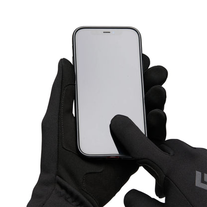 Person wearing black gloves holding a smartphone on a white background