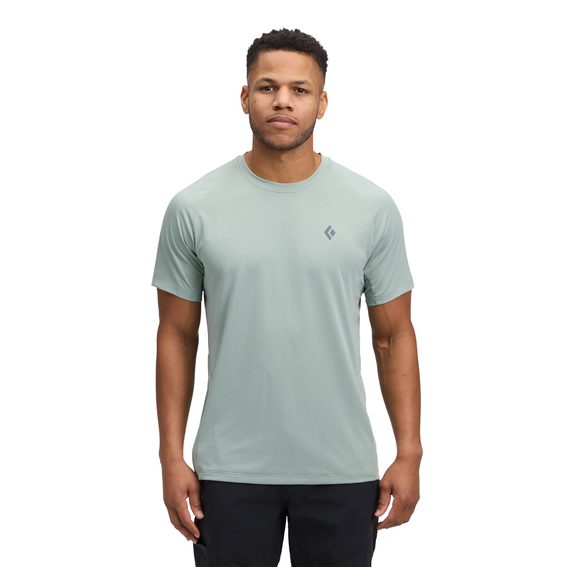 Man wearing a light green t-shirt with a small logo on a white background
