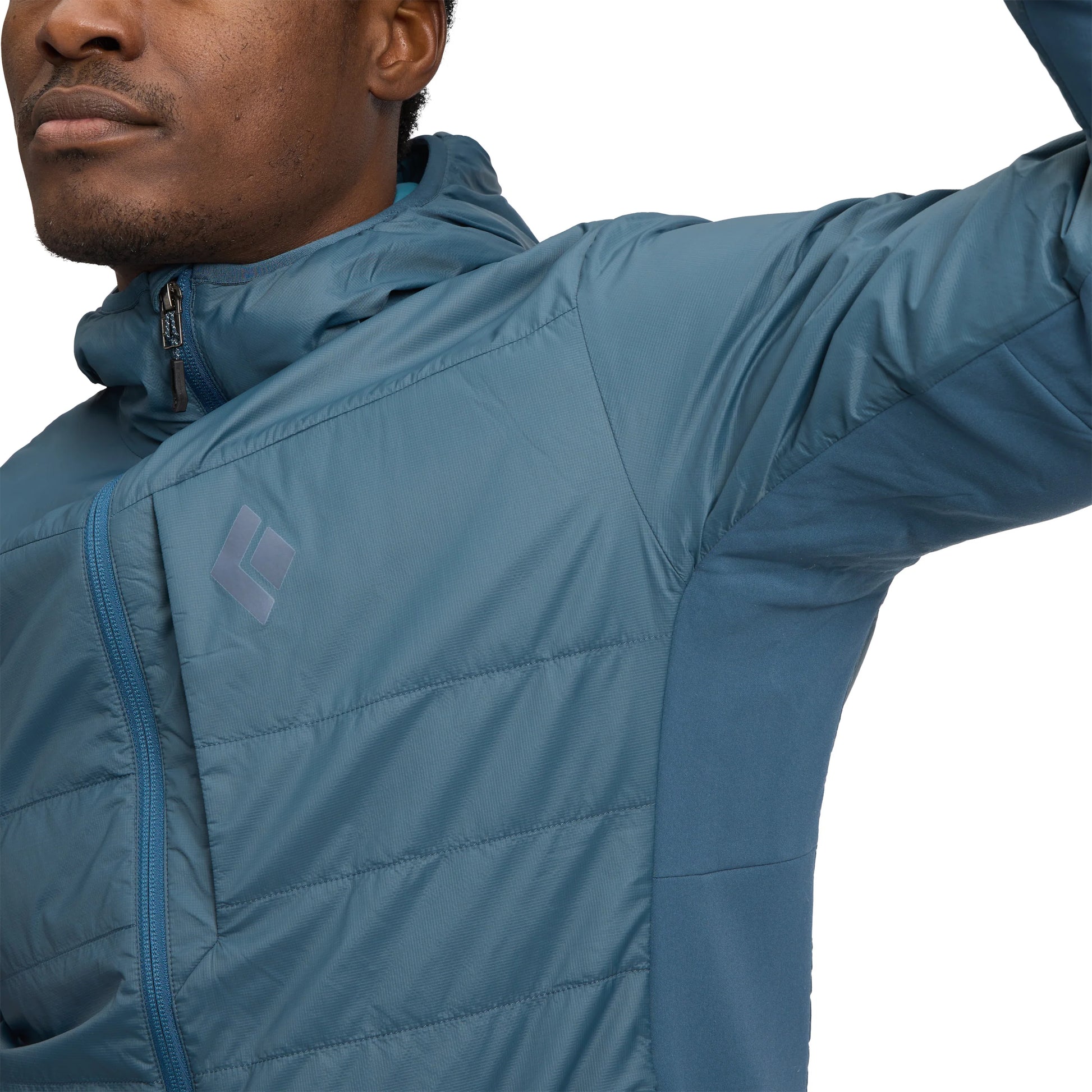 Close-up of a person wearing a blue quilted jacket with a brand logo.