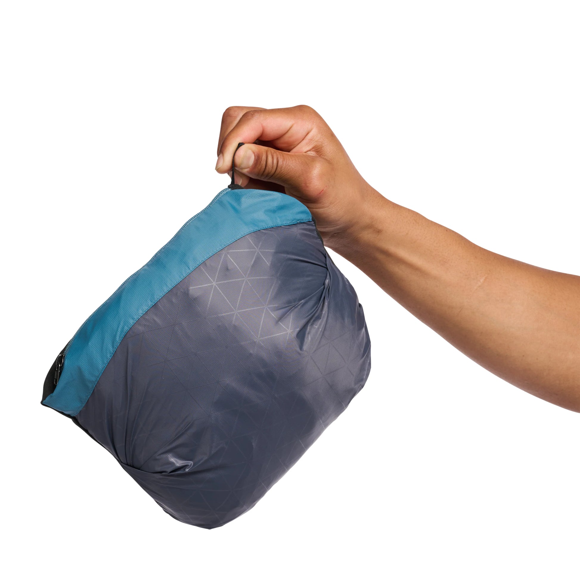 Hand holding a gray and blue compression sack on a white background