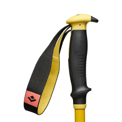 Yellow and black hiking pole with a strap on a white background