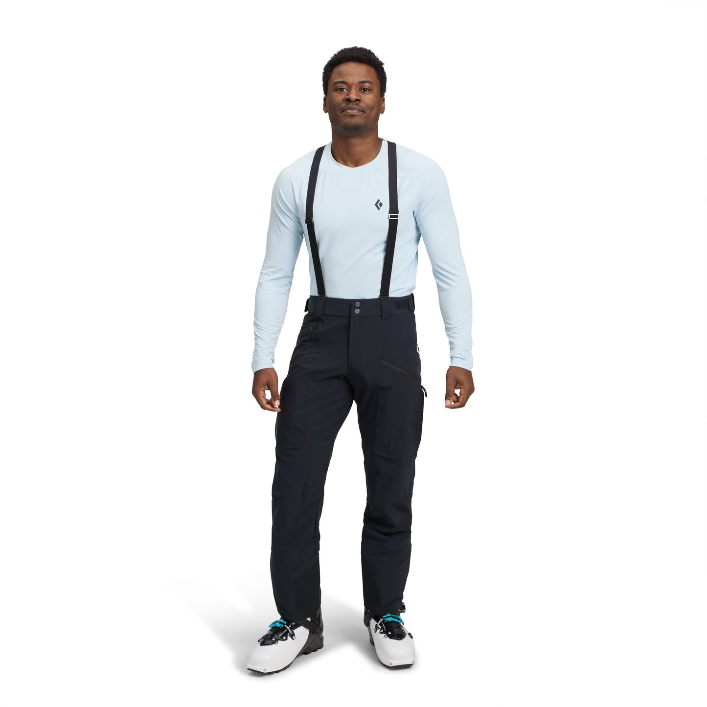 Person wearing a light blue long-sleeve shirt, black pants with suspenders, and white sneakers on a white background