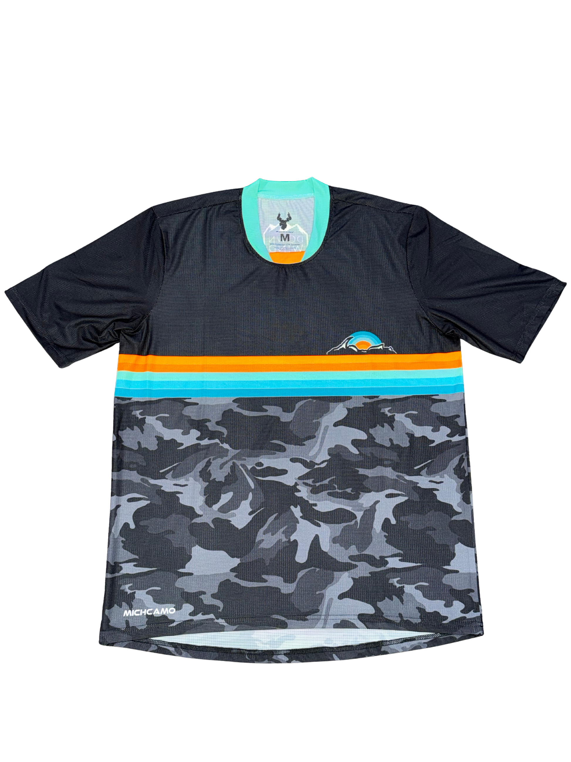 A short-sleeve athletic jersey with a black upper section, a horizontal stripe band in orange and turquoise, and a gray/black camouflage pattern on the lower half. The brand name 'Machete Apparel' is visible near the bottom left hem.