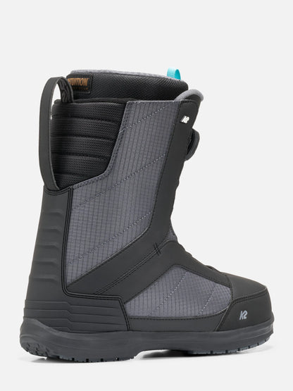 A single snowboard boot in dark gray and black with textured panels, a pull tab, and a small blue accent near the collar, shown on a light gray background.