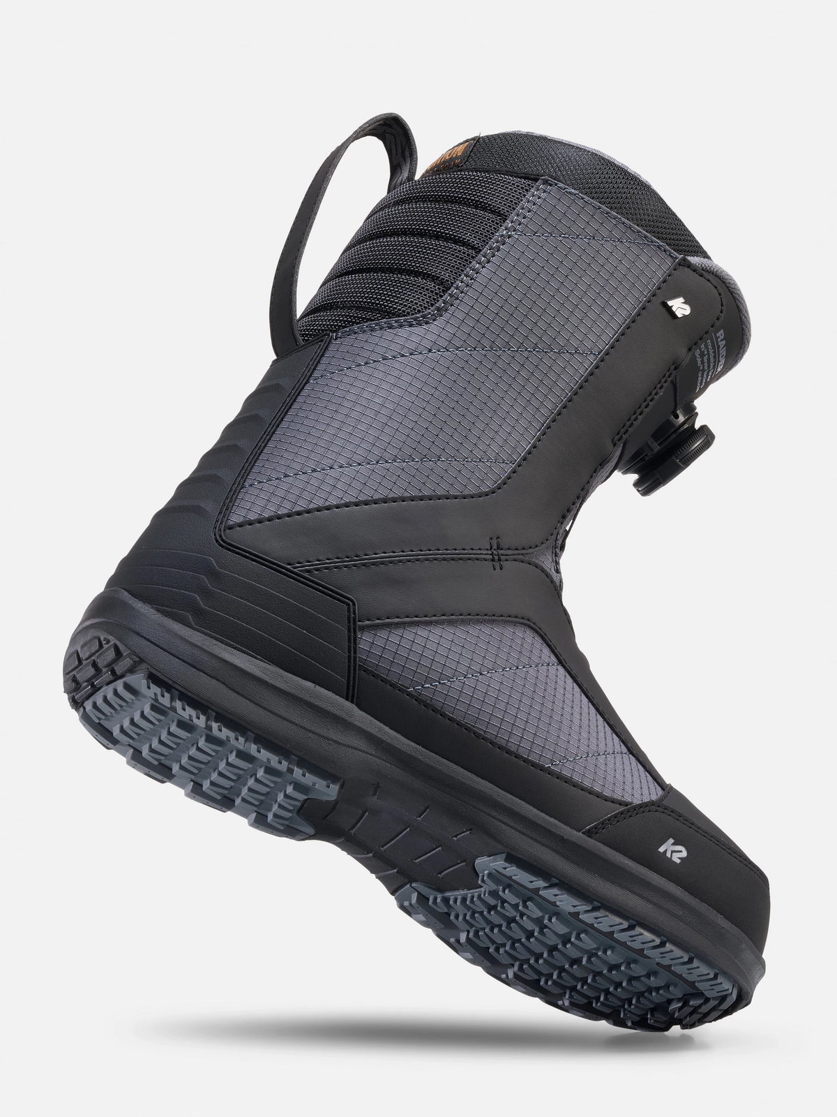 A single high-top snowboard boot in black and dark gray, shown floating at an angle against a light gray background.