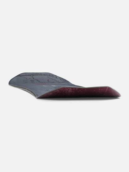A curved snowboard shown from the side against a plain light gray background, featuring a dark gray top sheet and a deep burgundy wood base.
