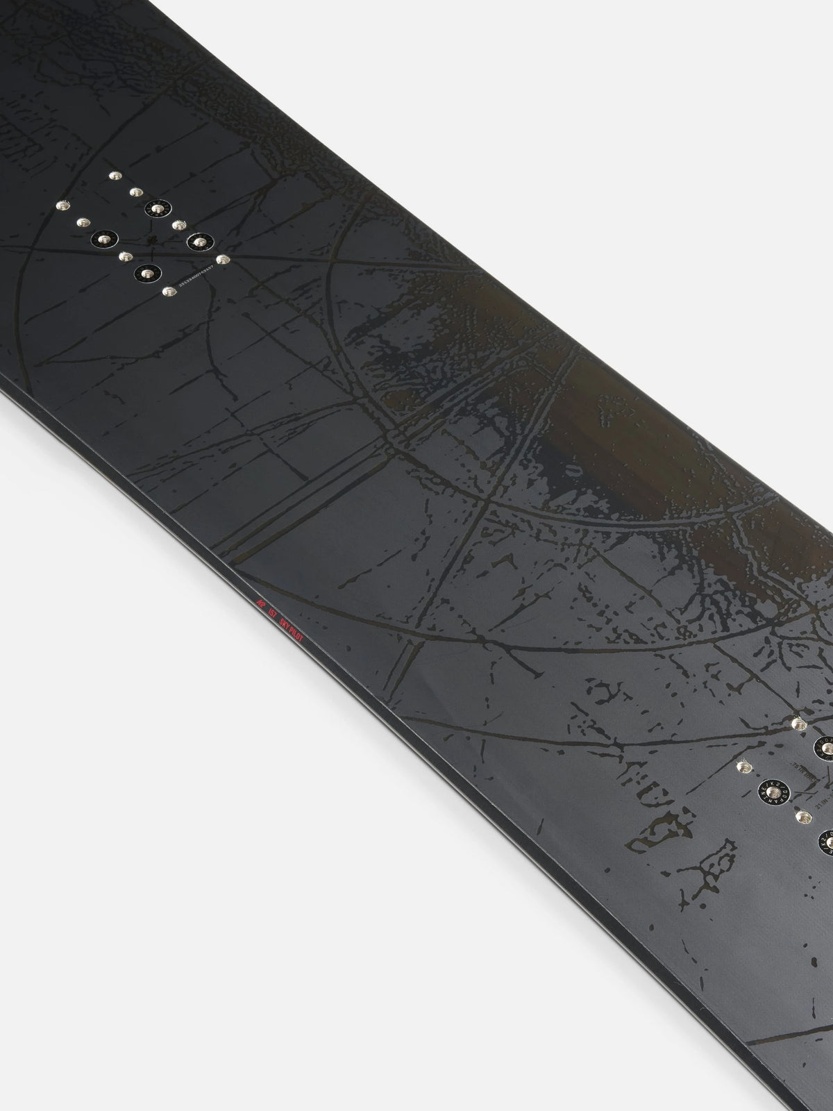 Close-up of a black snowboard with an embossed topographic map design and metal binding hardware, shown diagonally on a light gray background.