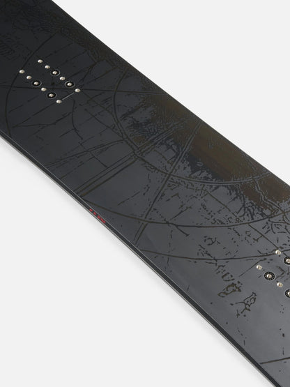 Close-up of a black snowboard with an embossed topographic map design and metal binding hardware, shown diagonally on a light gray background.