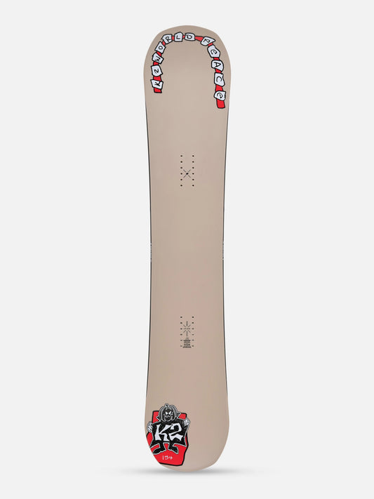 A snowboard shown from the base side, featuring a light beige background with red, white, and black graphics, including the 'K2' logo near the tail.