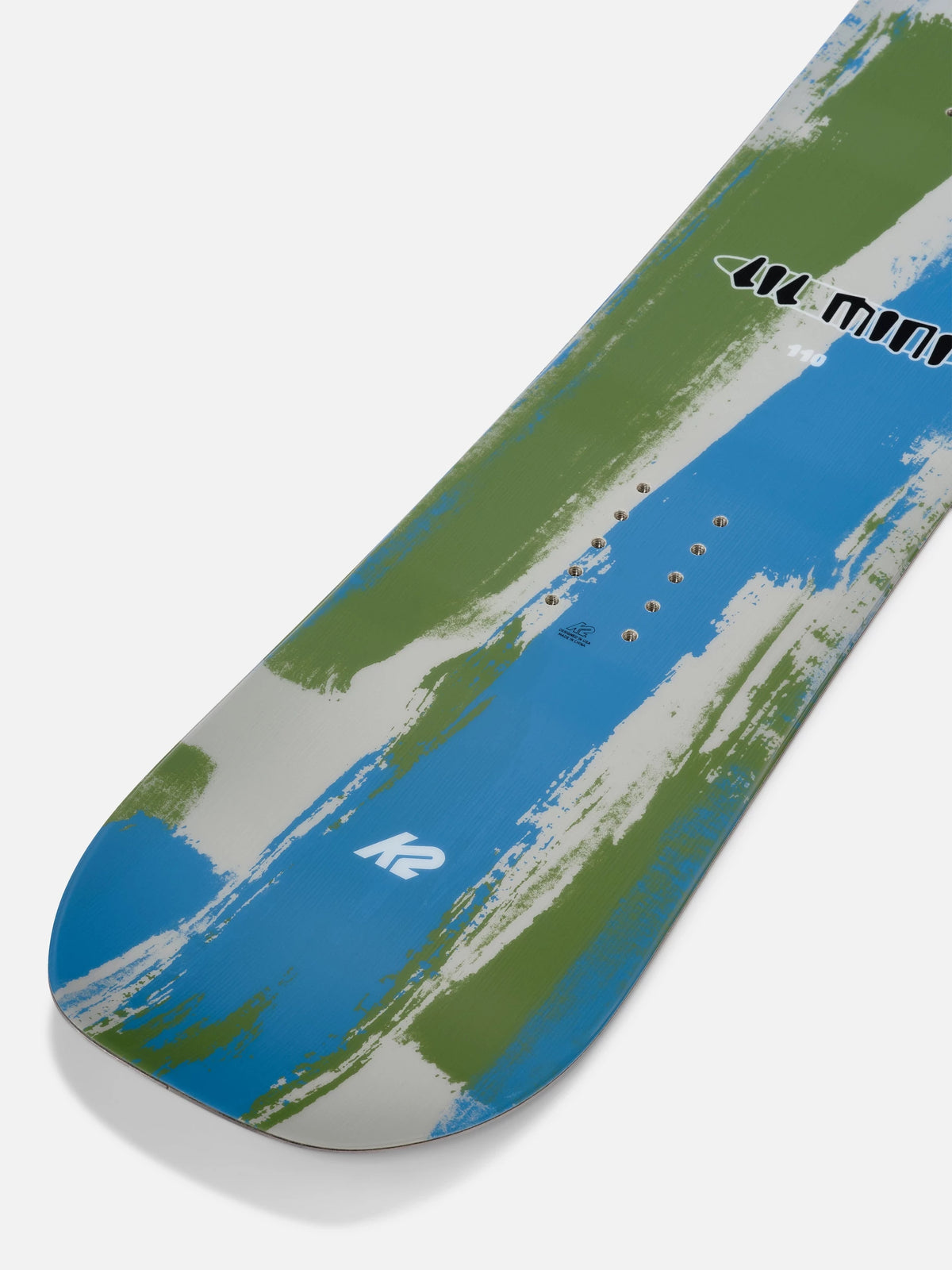 A close-up of a snowboard tail showing a blue, green, and white abstract brushstroke pattern with the K2 logo and 'K2 Mini' text.