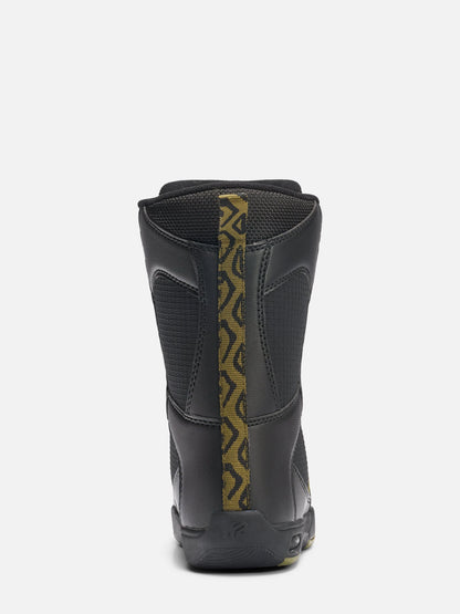 A black mid-calf boot shown from the back, featuring a textured black upper with a vertical gold and black geometric patterned stripe down the center and a black sole.