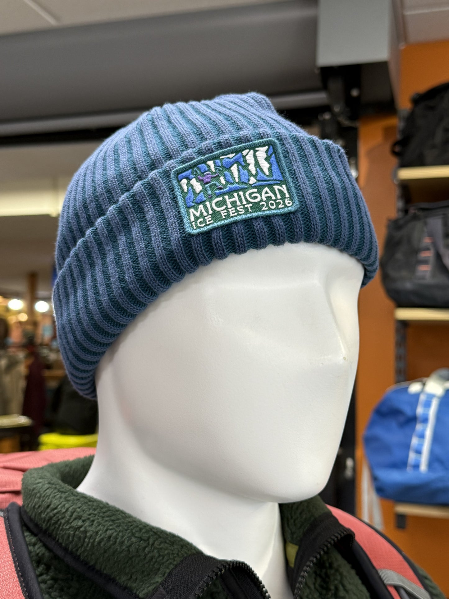 Blue knit beanie with 'Michigan Ice Fest 2026' patch on a mannequin head.