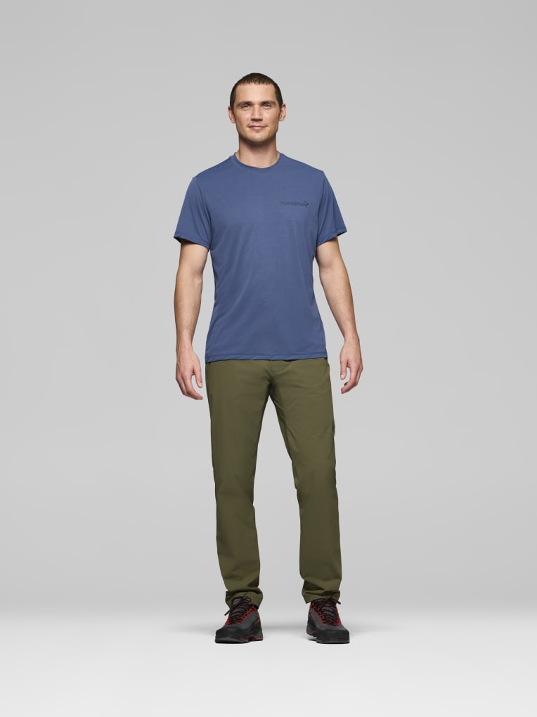Man wearing a blue t-shirt and green pants on a gray background