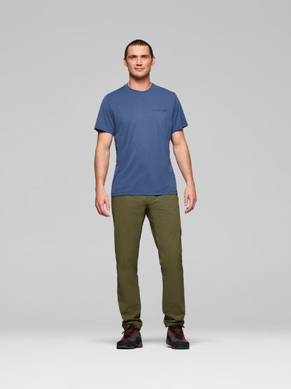 Man wearing a blue t-shirt and green pants on a gray background
