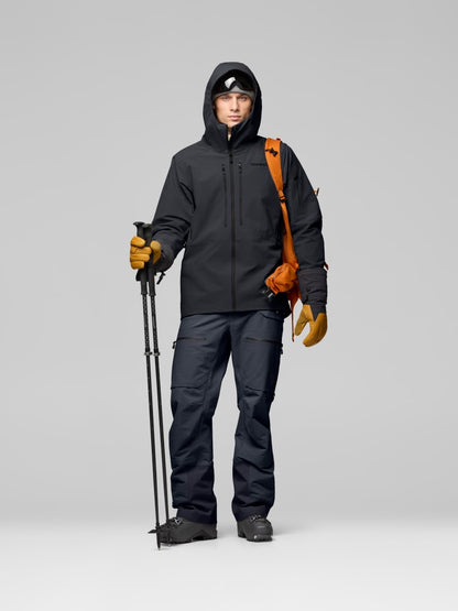 Person wearing a black jacket and pants with hiking gear on a gray background