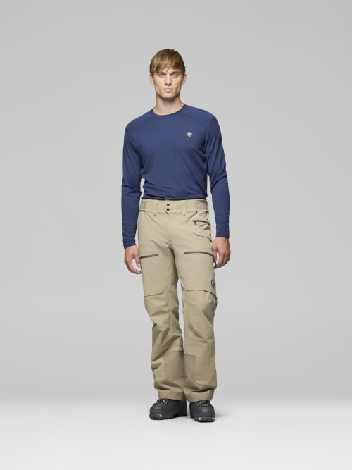 Man wearing a navy long-sleeve shirt and beige pants on a gray background