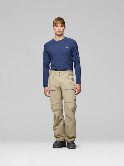 Man wearing a navy long-sleeve shirt and beige pants on a gray background