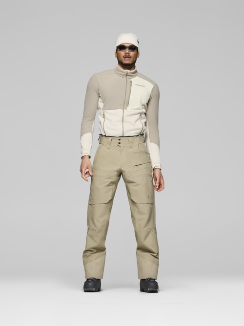 Person wearing a beige and white jacket with matching pants on a gray background