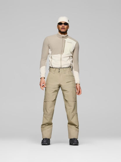 Person wearing a beige and white jacket with matching pants on a gray background