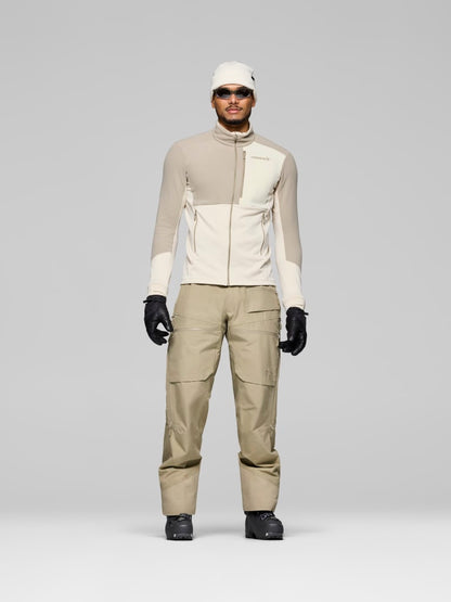 Person wearing a beige and white jacket with matching pants on a gray background