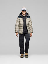 Load image into Gallery viewer, Person wearing a beige puffer jacket, black shirt, pants, and shoes on a gray background
