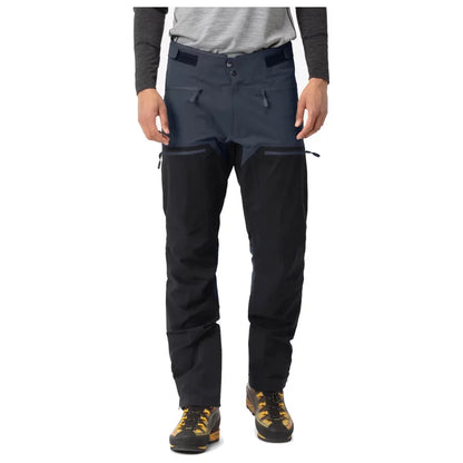 Person wearing dark gray pants with black zippers on a white background