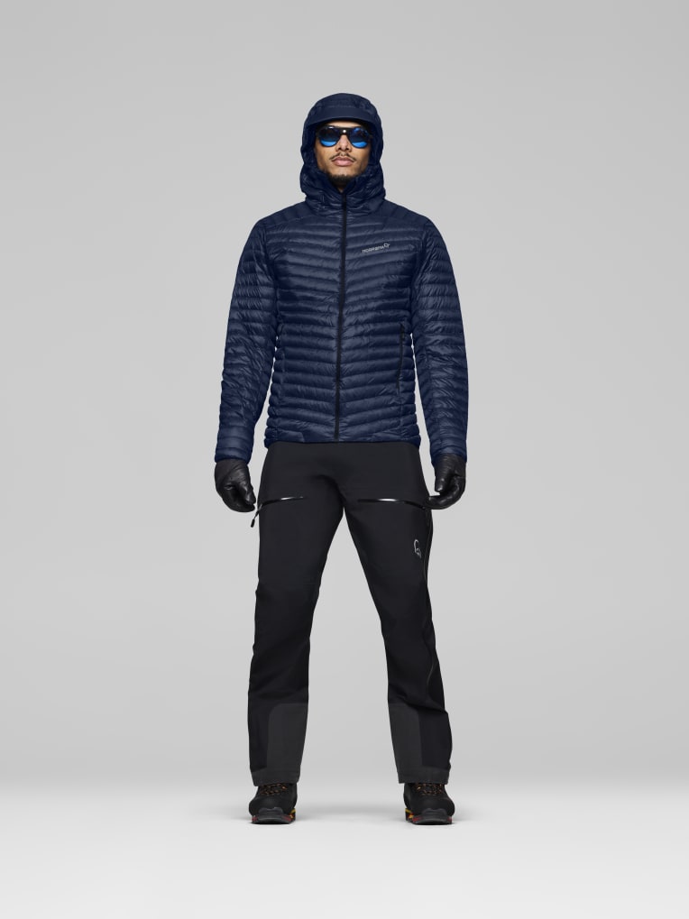 Person wearing a dark blue jacket and black pants on a gray background