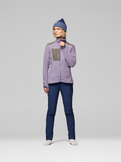 Person wearing a purple jacket and blue pants with a matching beanie on a light gray background